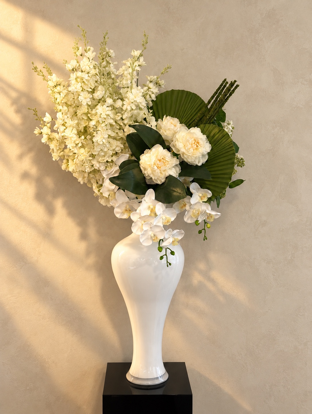 Camille Lopez's asymmetric ivory floral arrangement with sculptural green foliage, cascading orchids, and a tall white vase